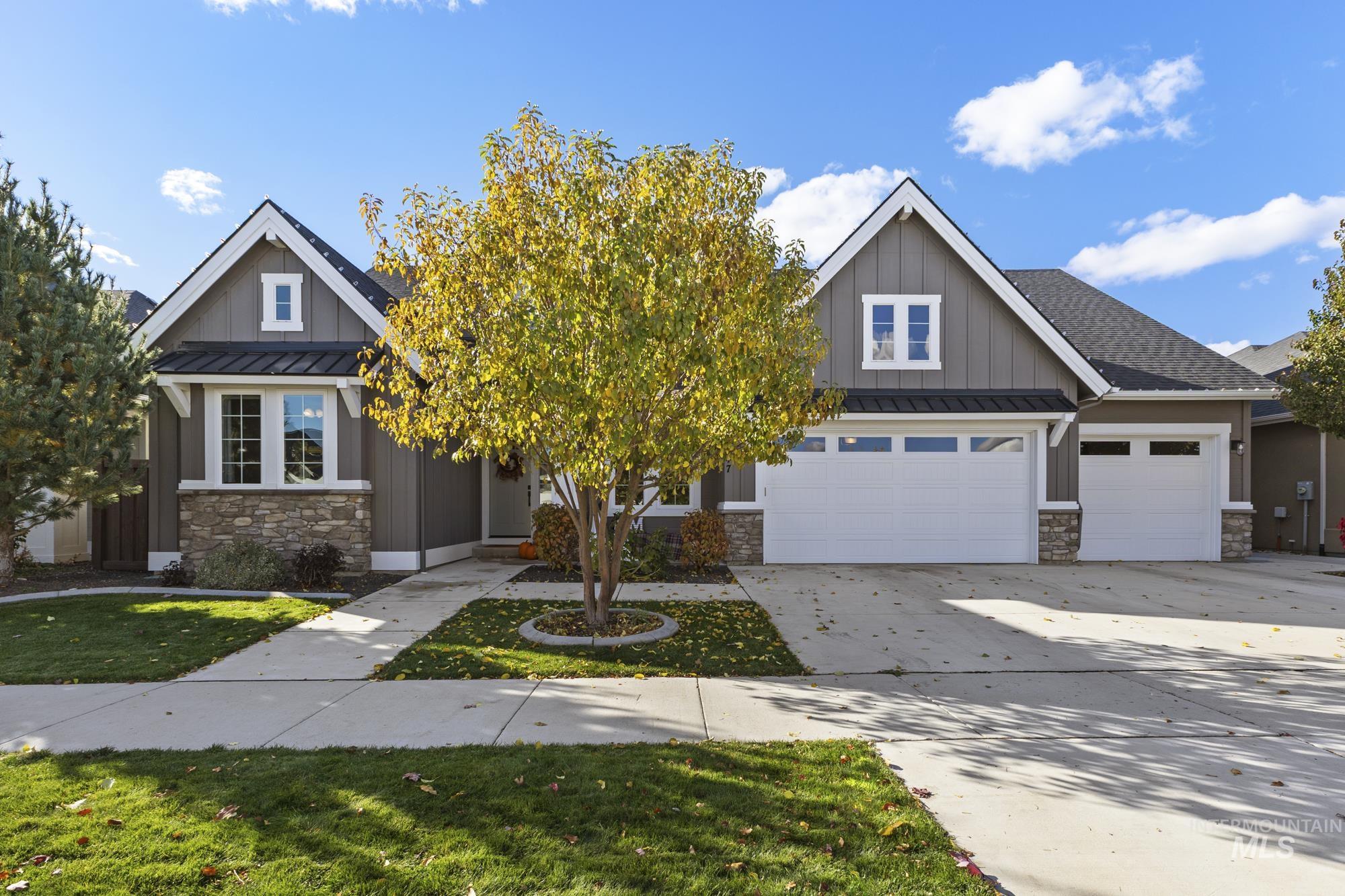 Craftsman inspired home with a standing seam roof, board and batten siding, a metal roof, stone siding, and a garage