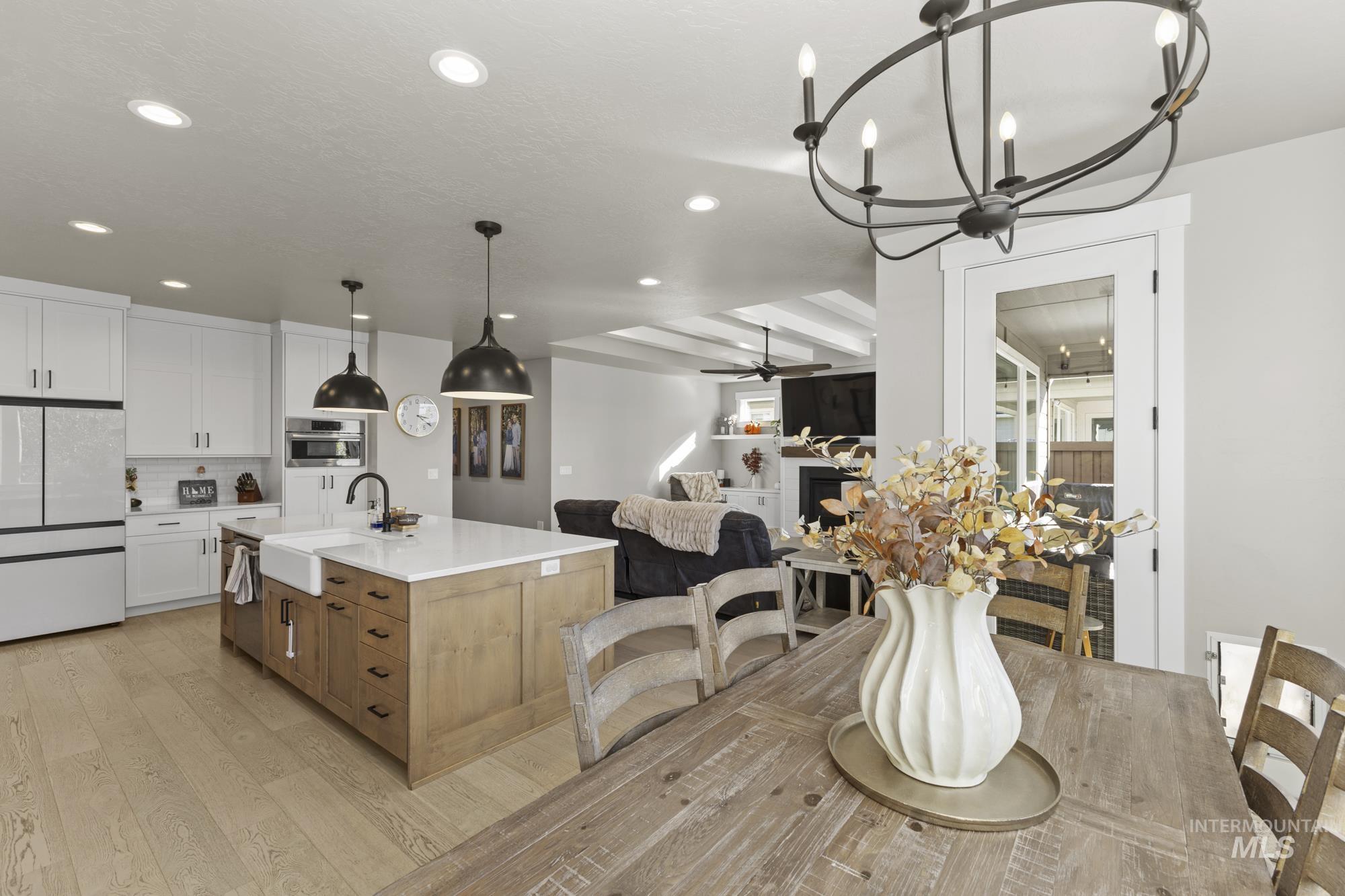 Dining room featuring a fireplace, a chandelier, light wood-type flooring, recessed lighting, and a ceiling fan
