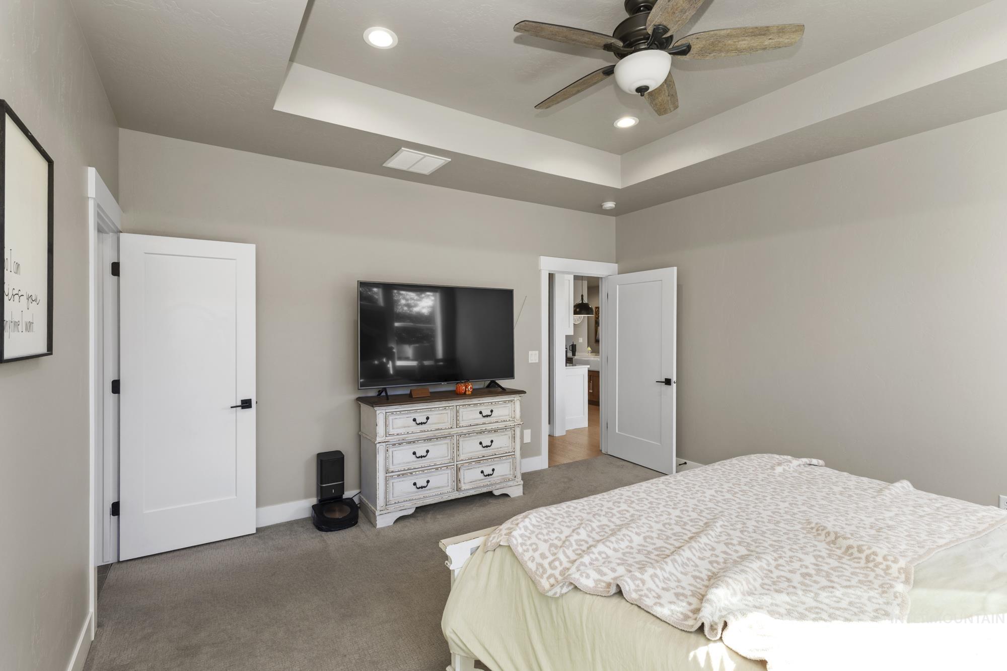Carpeted bedroom with a tray ceiling, recessed lighting, and ceiling fan