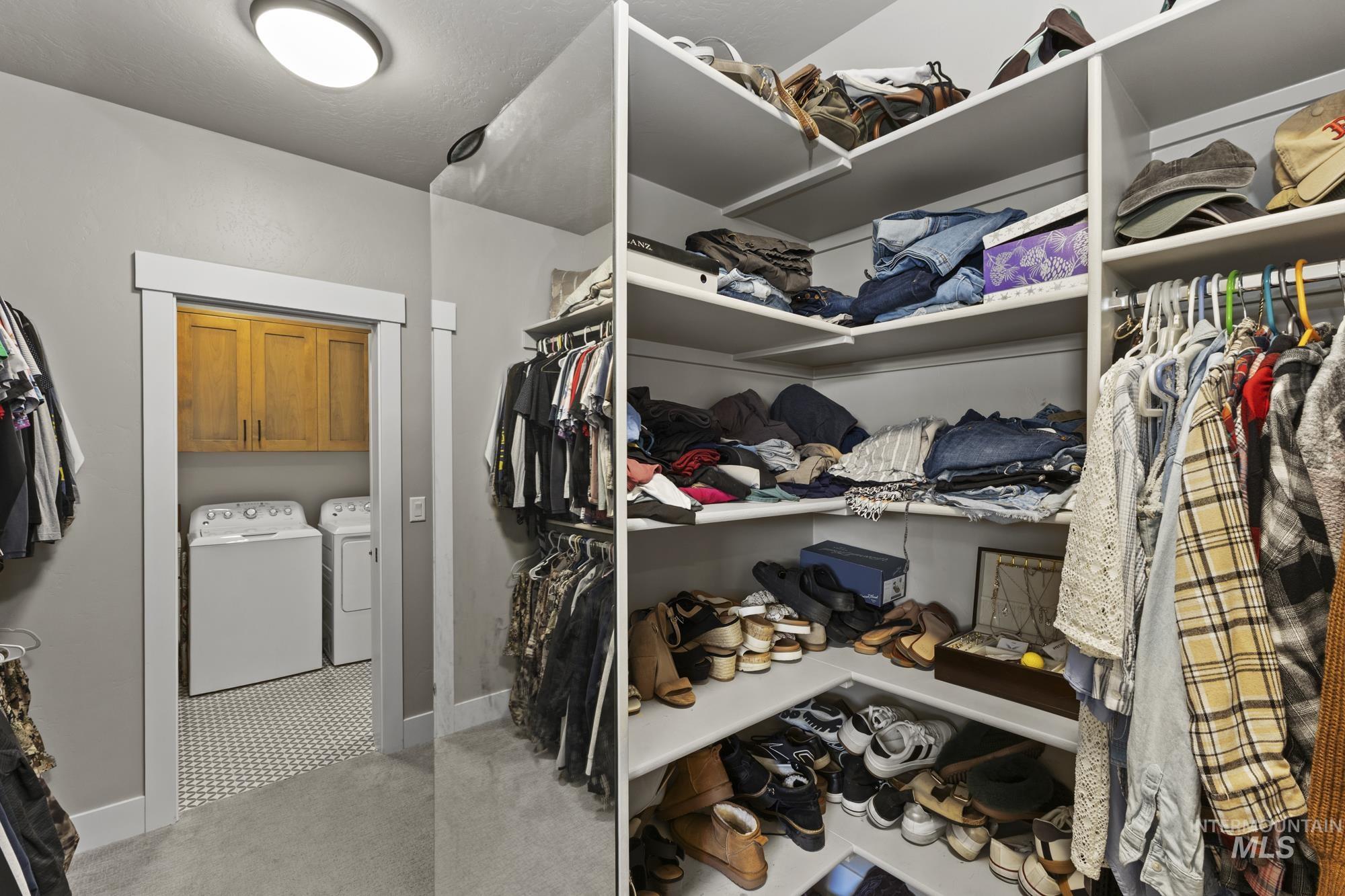 Walk in closet featuring light colored carpet and independent washer and dryer