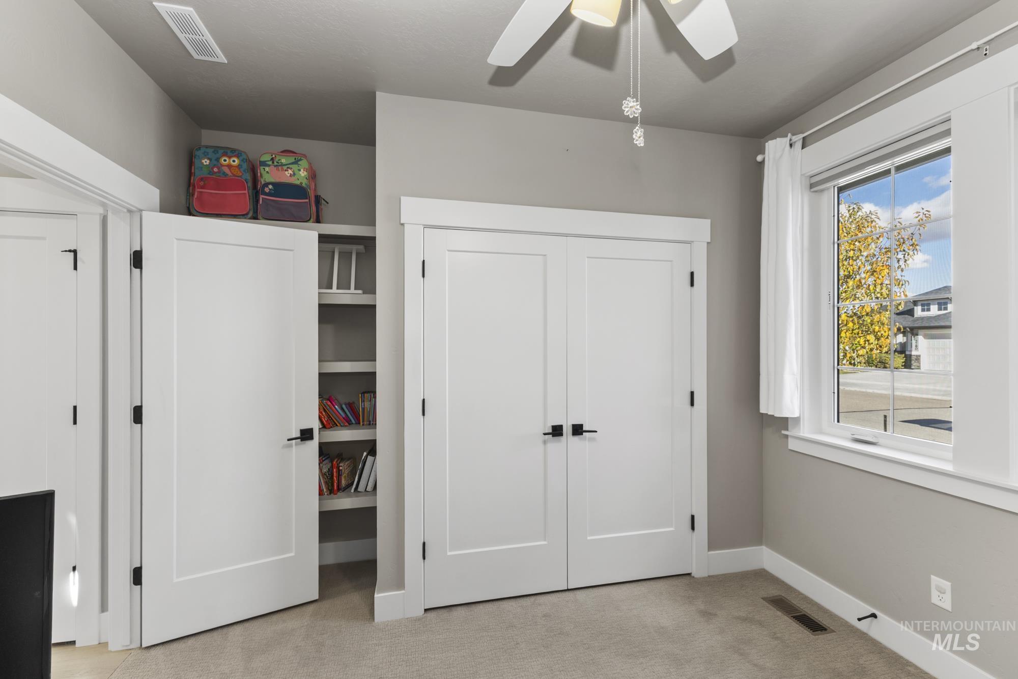 Unfurnished bedroom featuring light colored carpet, a closet, and a ceiling fan