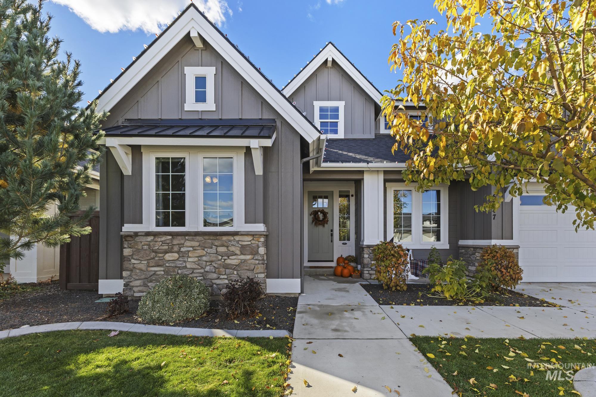 View of front facade with stone siding, board and batten siding, a standing seam roof, and roof with shingles