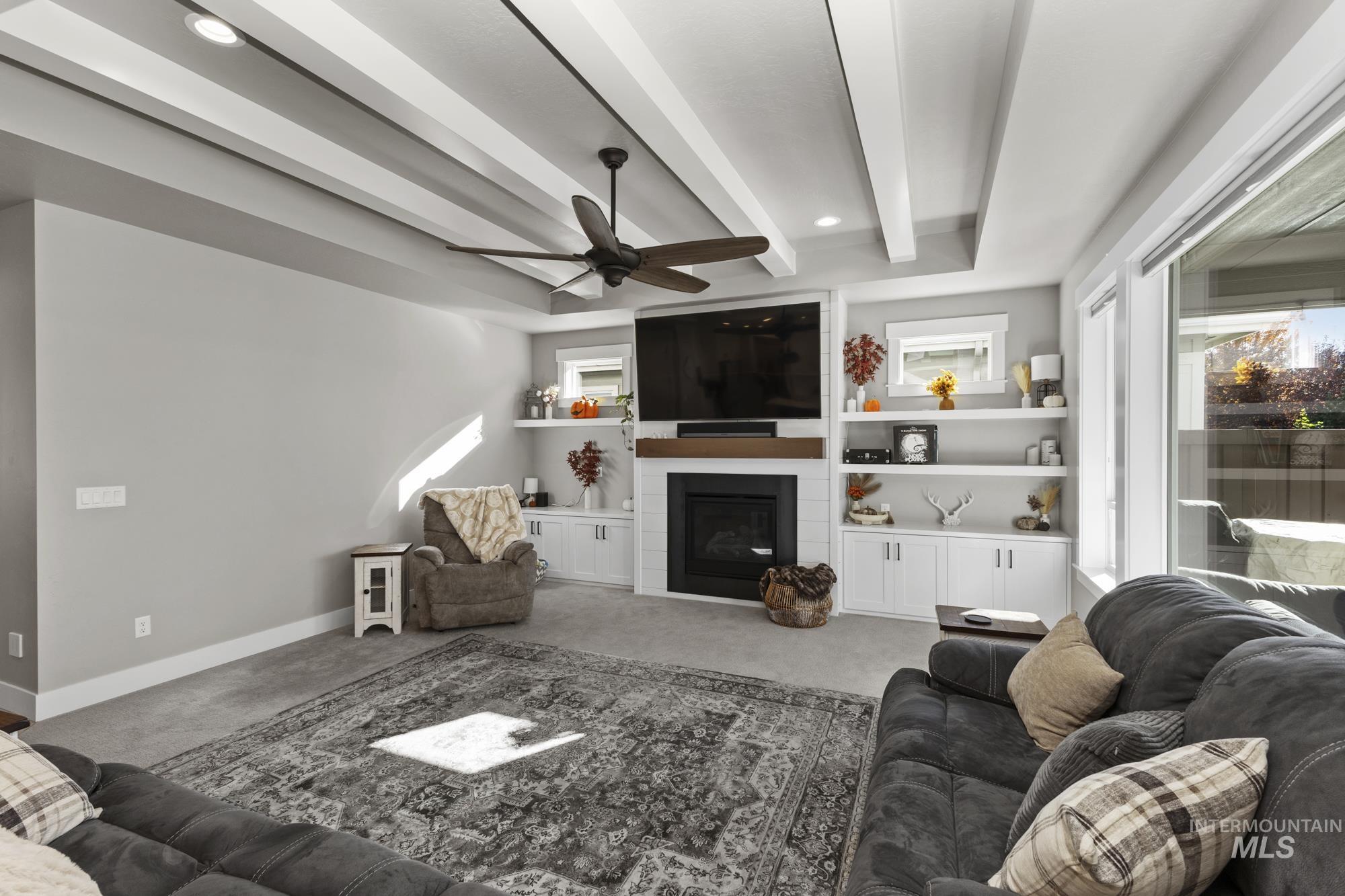 Living area featuring beamed ceiling, carpet flooring, a fireplace, ceiling fan, and recessed lighting