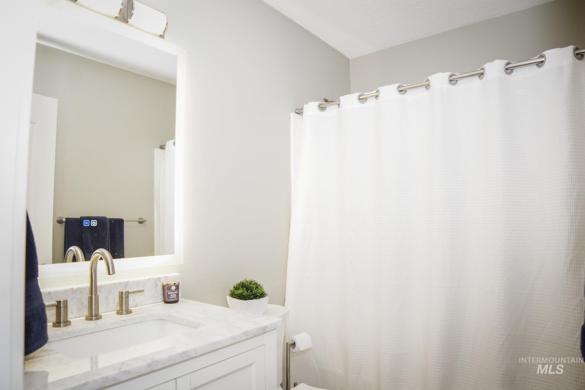 Vanity featuring a rectangular undermount sink, a polished nickel widespread faucet, and a stone countertop