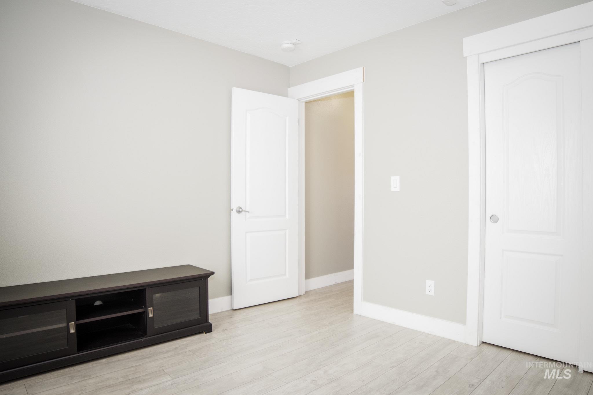 Interior room featuring light gray walls and wood-finish flooring