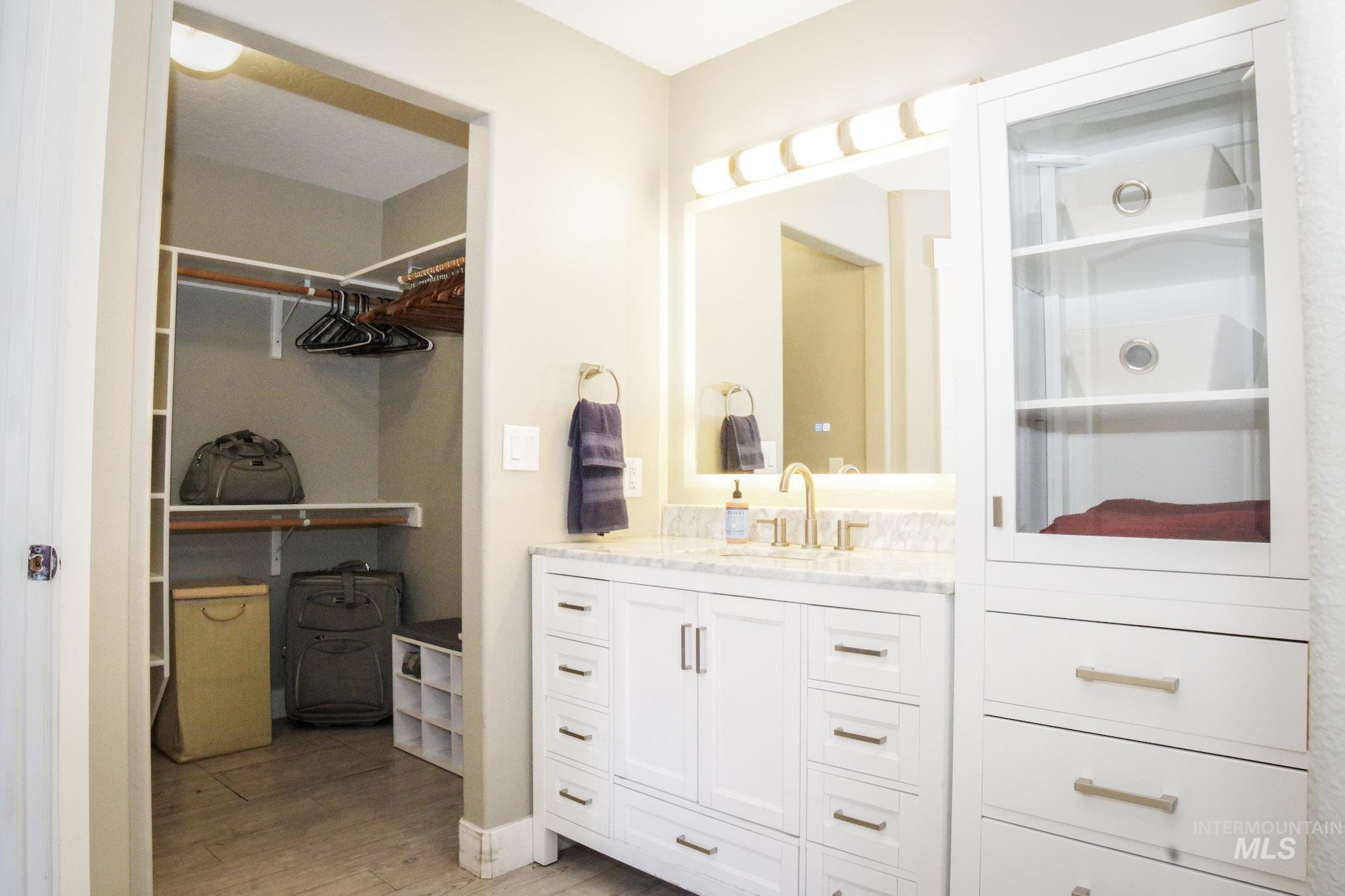 Bathroom vanity with a white shaker-style cabinet, light-toned countertop, and gold-finish faucet