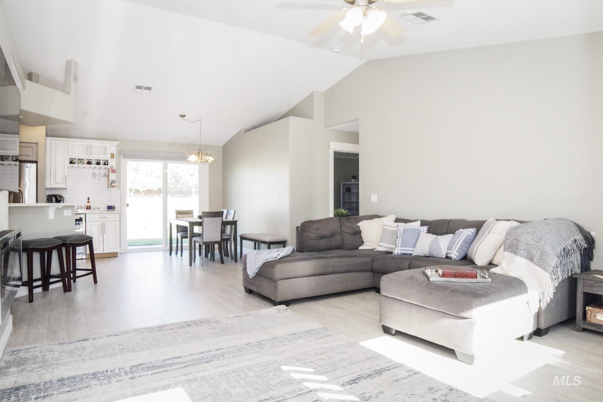 Spacious open-concept living area featuring vaulted ceilings and light wood-finish flooring