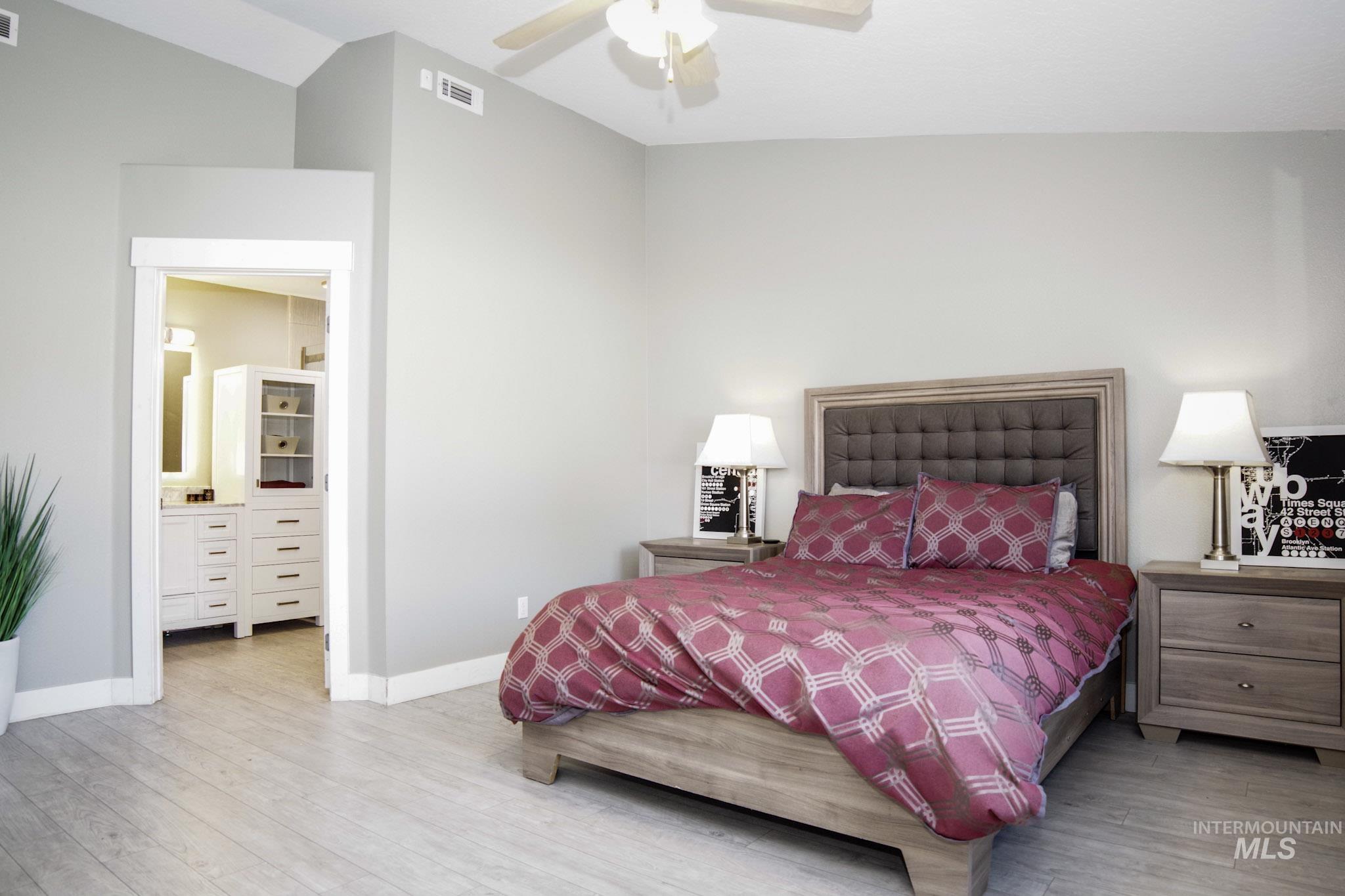 Spacious room featuring vaulted ceilings, light wood-finish flooring, and a modern ceiling fan with integrated lighting