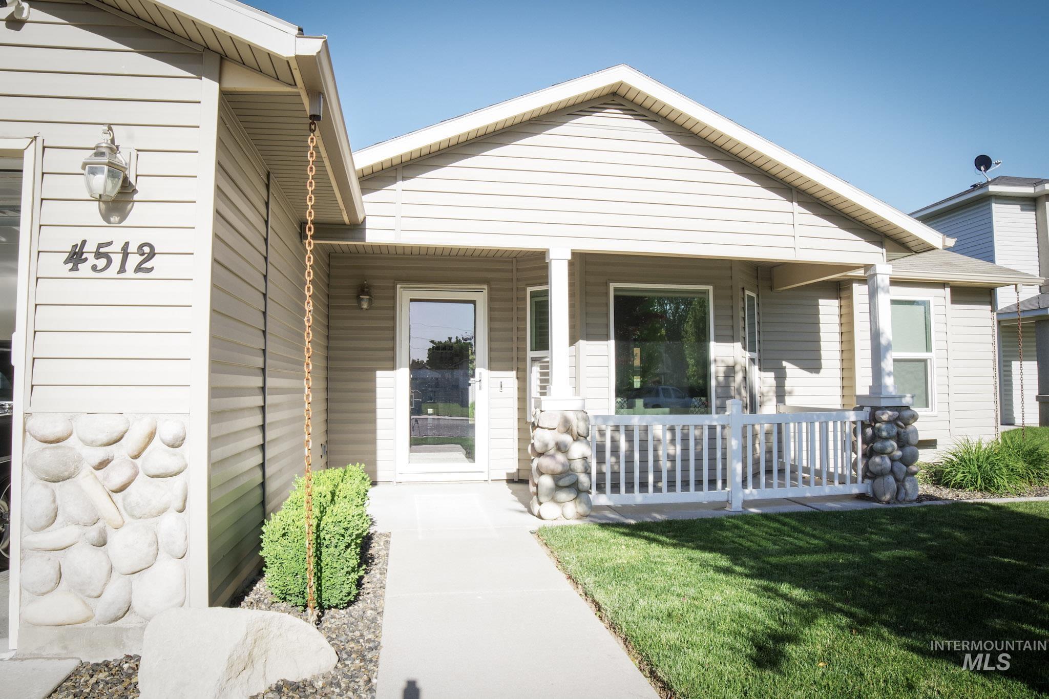 Front exterior featuring horizontal siding, a covered porch with stone-wrapped columns, a white railing, and a clear glass entry door