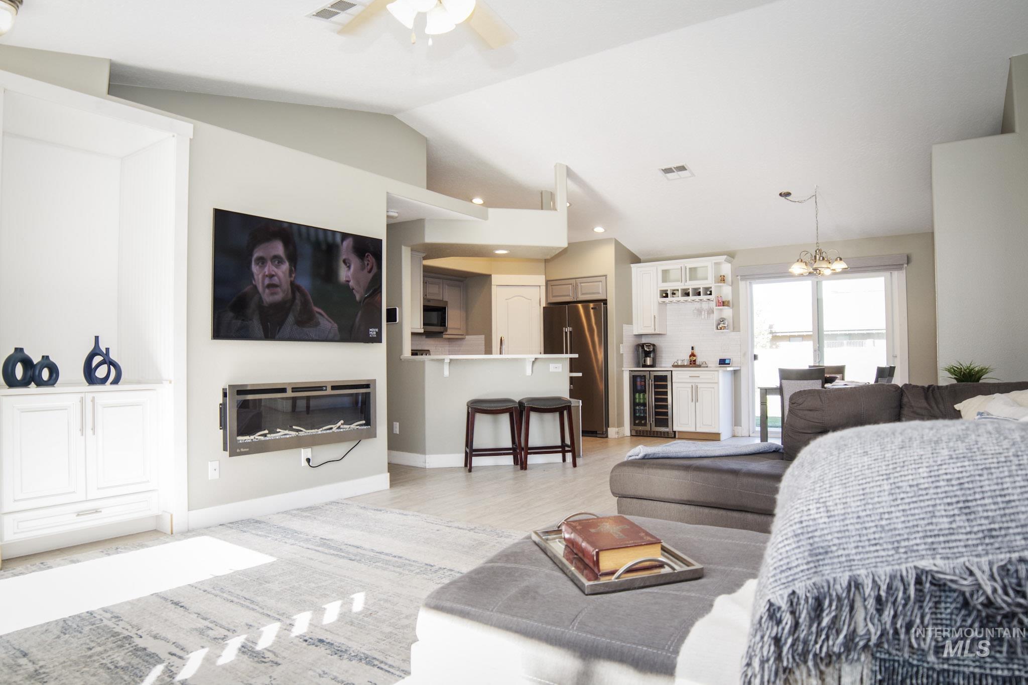 Spacious living area featuring vaulted ceilings, a wall-mounted electric fireplace, and built-in cabinetry
