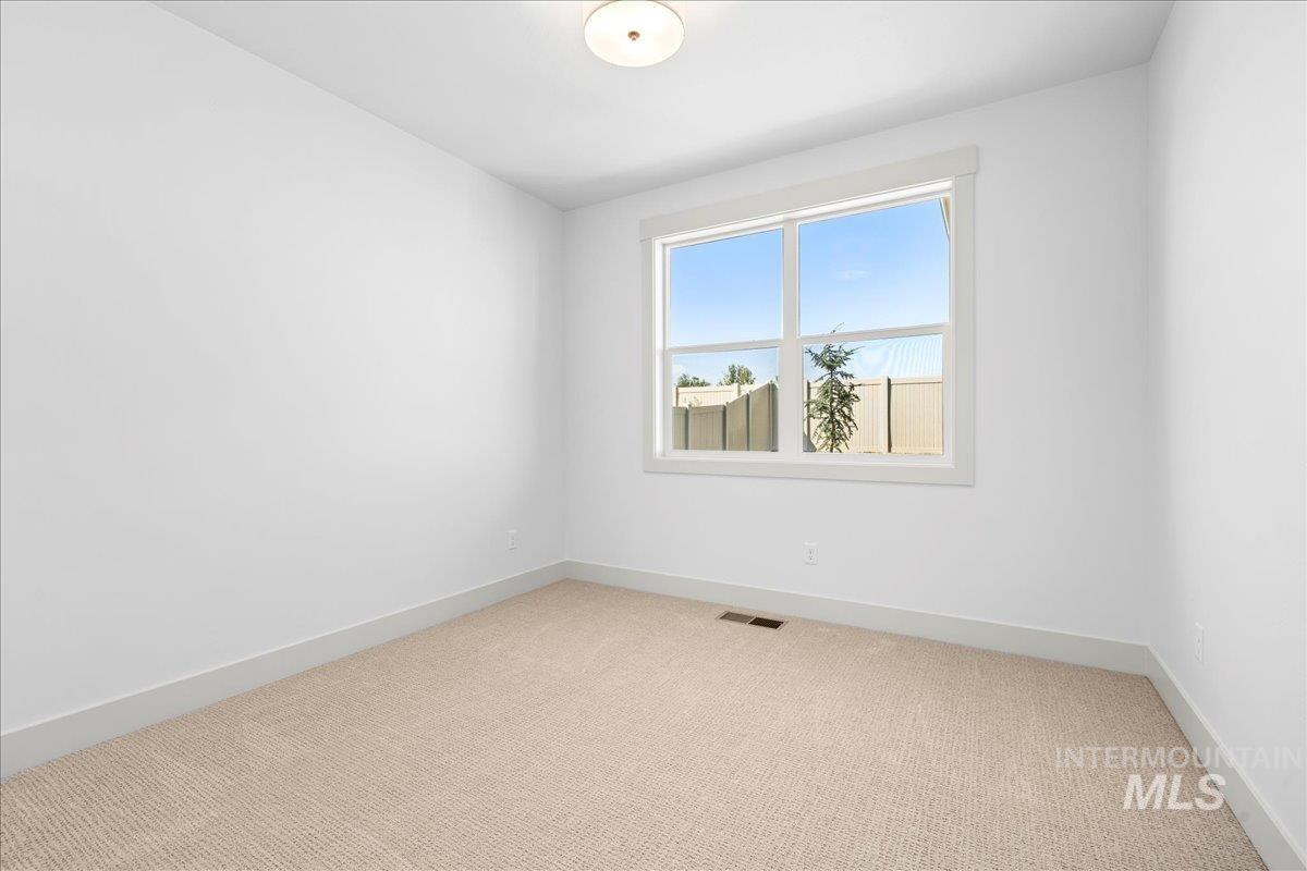 Spare room featuring light colored carpet and baseboards