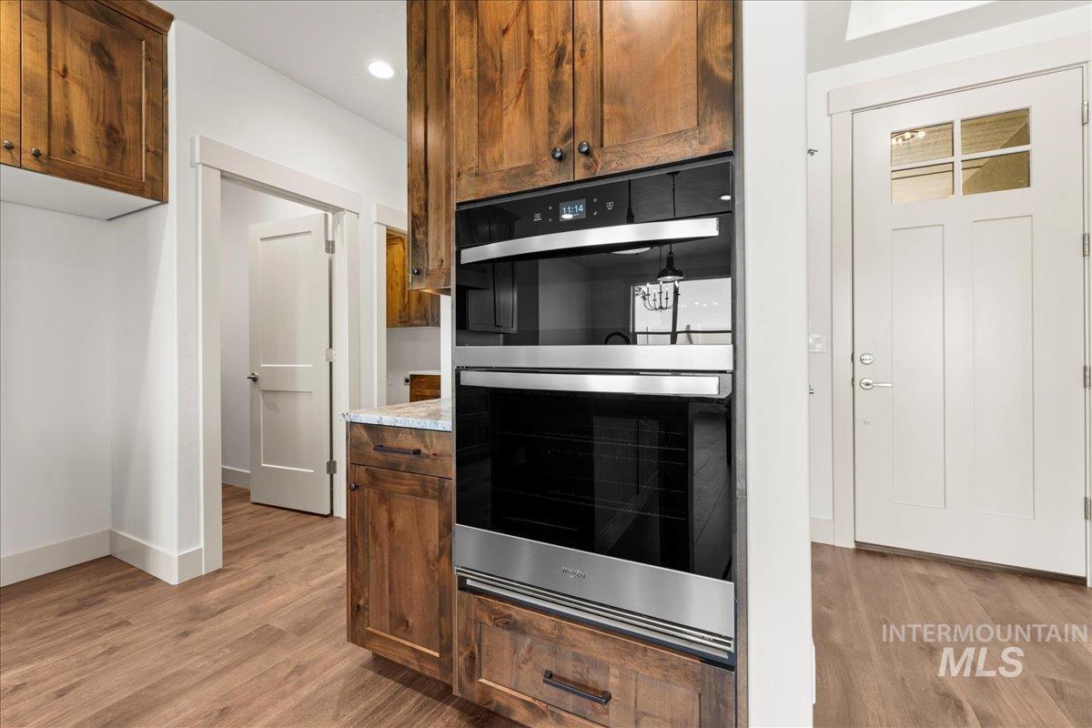 Kitchen featuring double oven, light wood-style flooring, light countertops, and recessed lighting