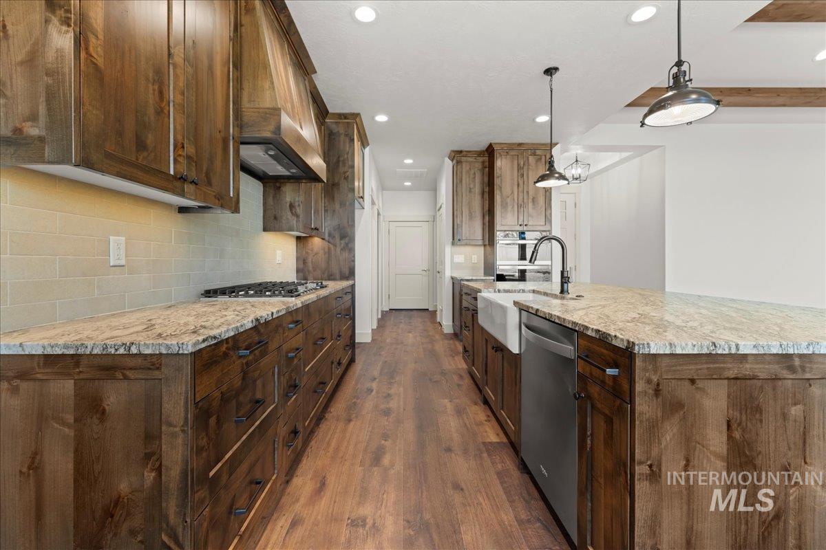 Kitchen featuring recessed lighting, dark wood-type flooring, decorative backsplash, stainless steel appliances, and premium range hood