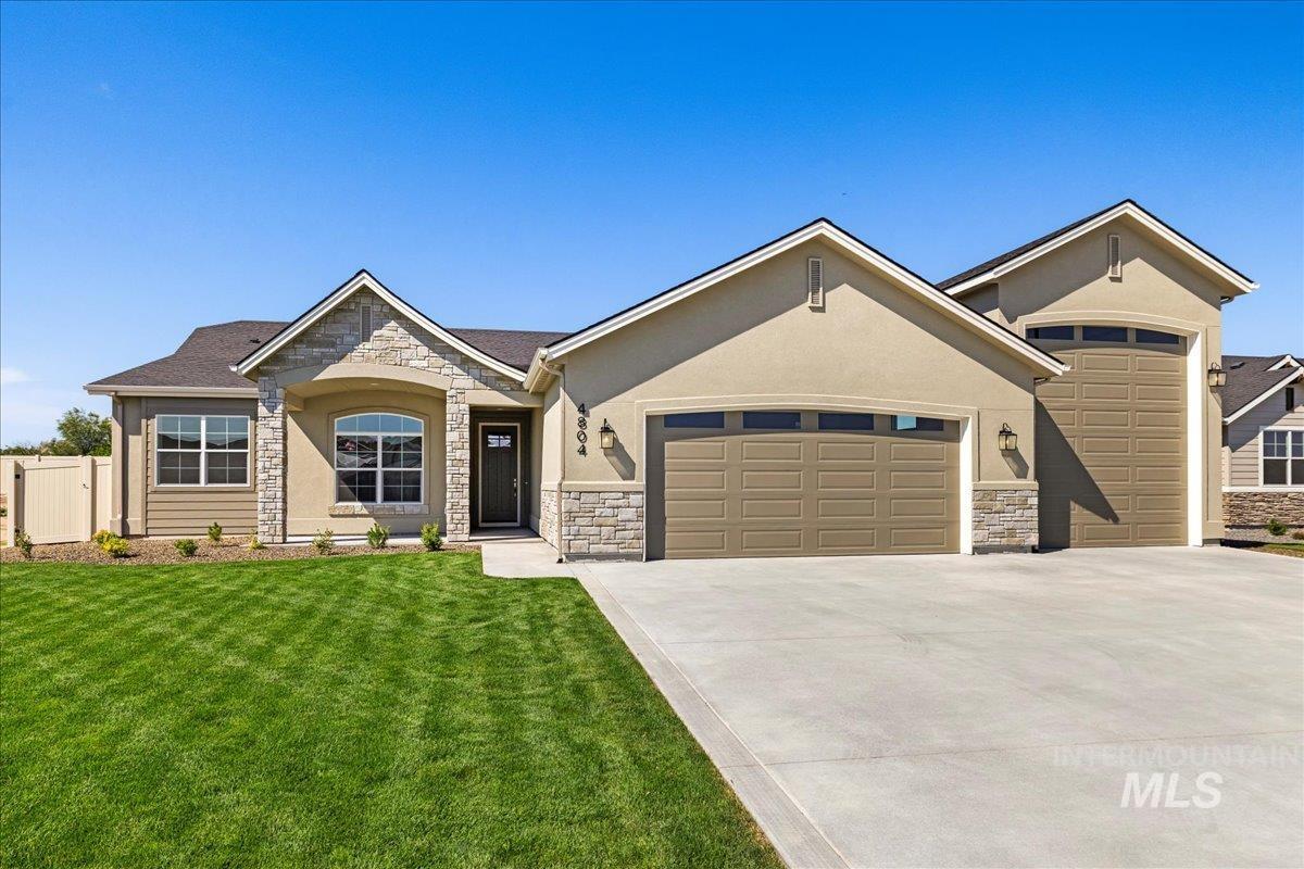 View of front of house featuring an attached garage, stone siding, concrete driveway, and stucco siding