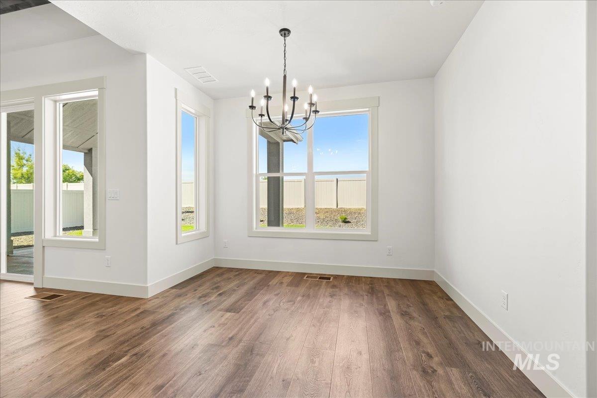 Unfurnished dining area featuring a chandelier and wood finished floors