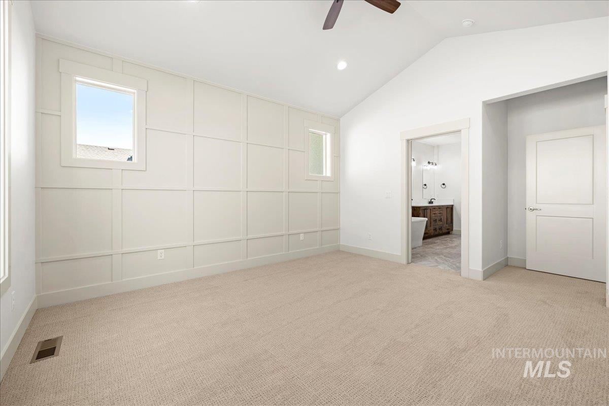 Unfurnished bedroom with carpet floors, lofted ceiling, multiple windows, recessed lighting, and ensuite bathroom