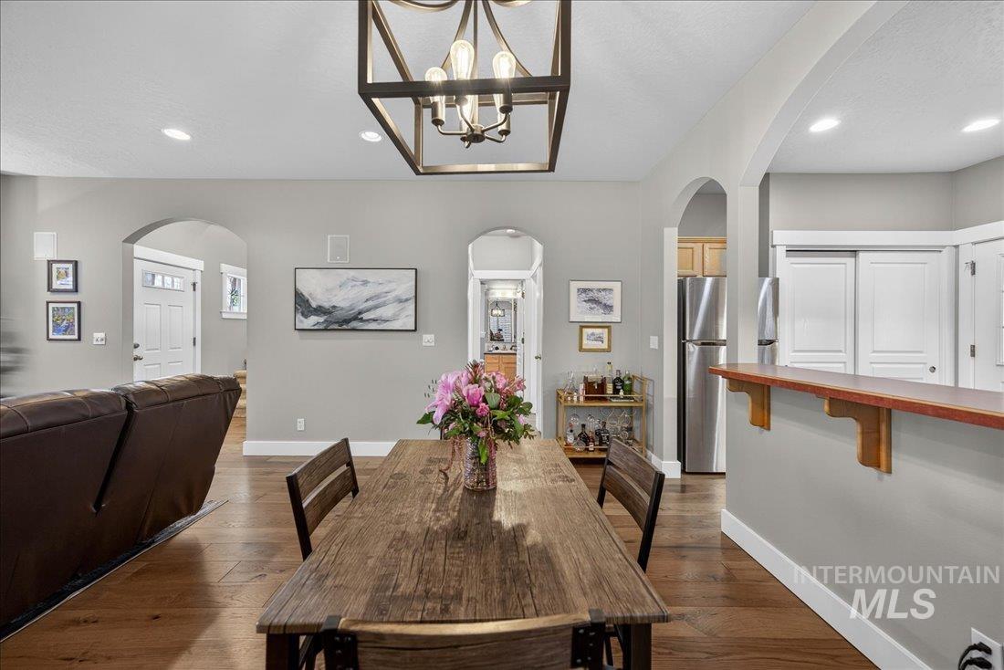 Dining area featuring suspended lighting, arched walkways, and dark wood-type flooring