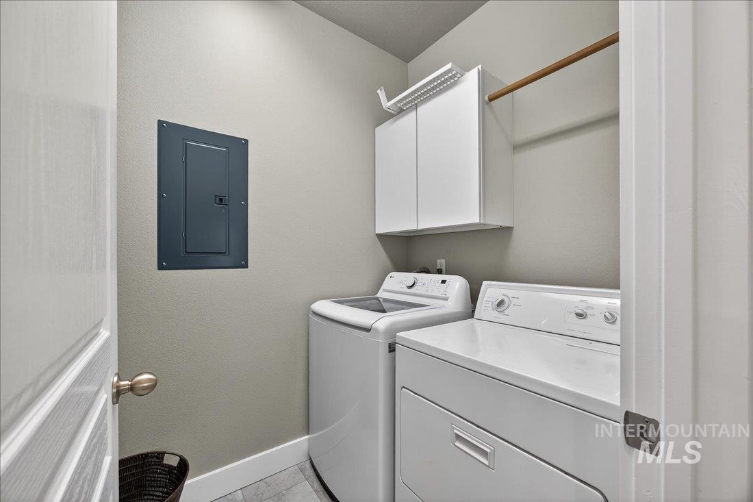 Downstairs laundry room with electric panel, cabinet space, independent washer and dryer, and a textured wall