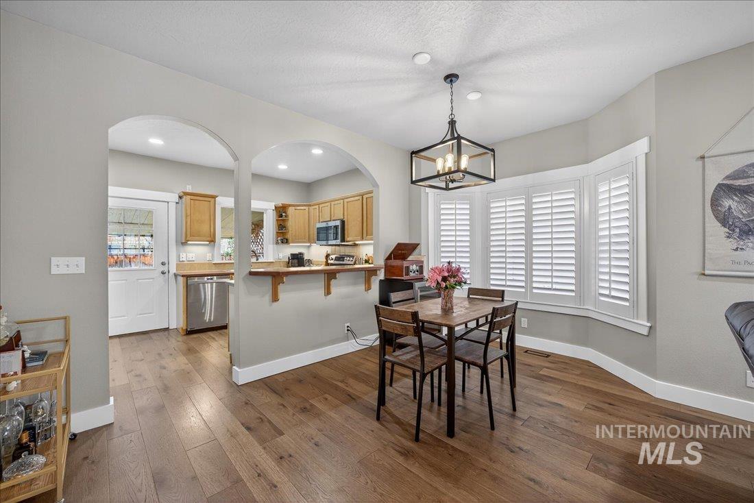Dining room featuring dark wood-type flooring, healthy amount of natural light, and arched walkways
