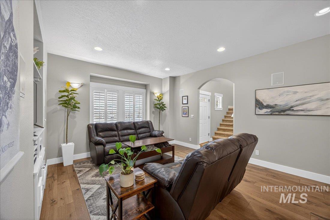 Living area with hardwood / wood-style floors, arched walkways, recessed lighting, and a textured ceiling