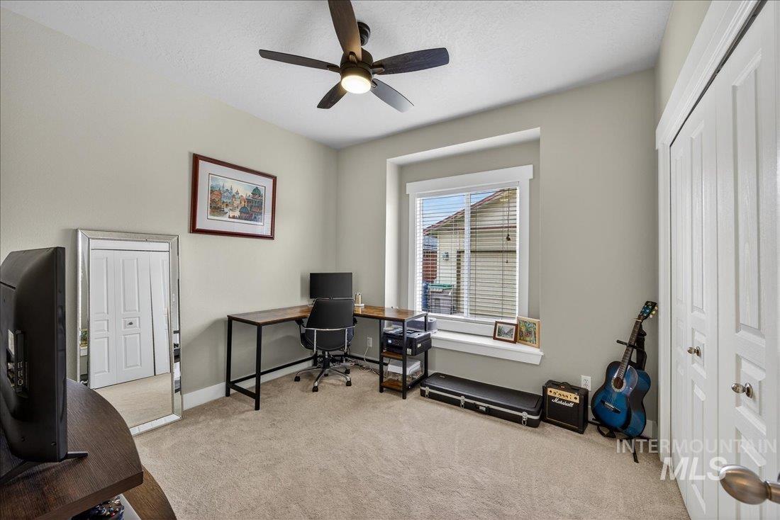 Downstairs bedroom featuring light colored carpet, ceiling fan, and a textured ceiling