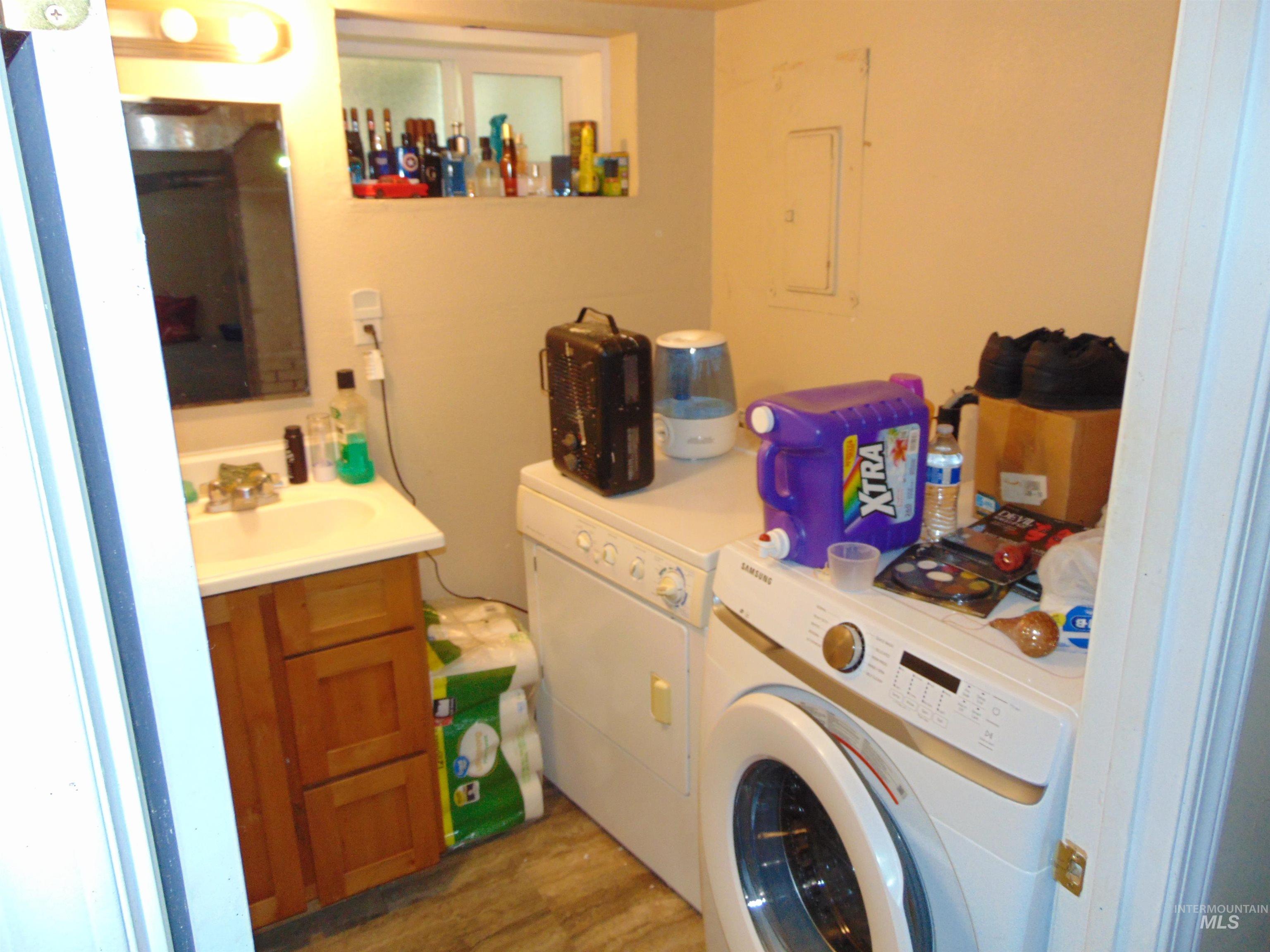 Laundry room featuring wood finished floors, electric panel, and washer and clothes dryer