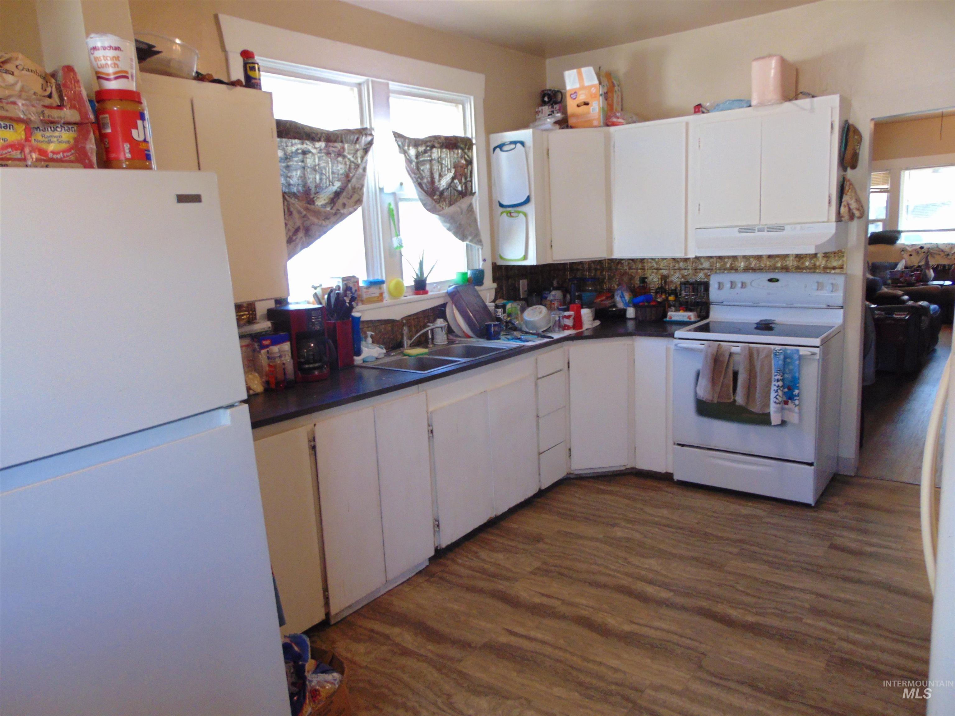 Kitchen featuring white appliances, dark countertops, and dark wood finished floors