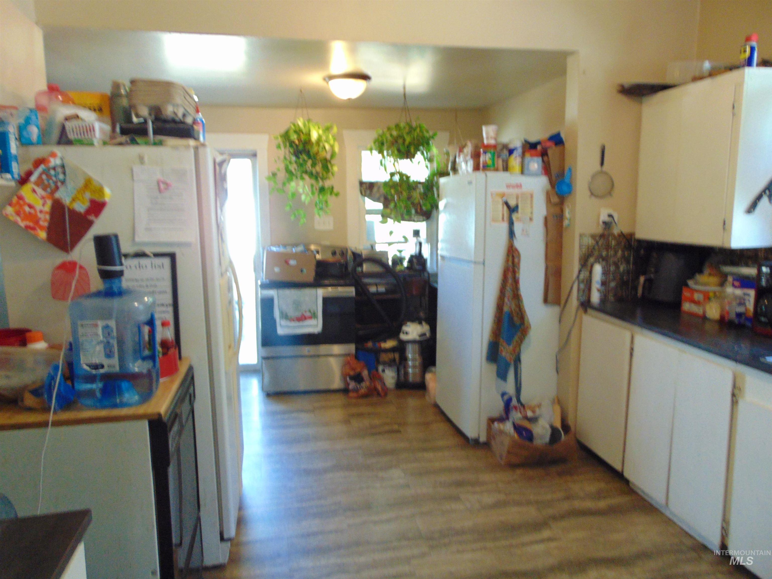 Kitchen with dark countertops, freestanding refrigerator, white cabinetry, and stainless steel range with electric cooktop
