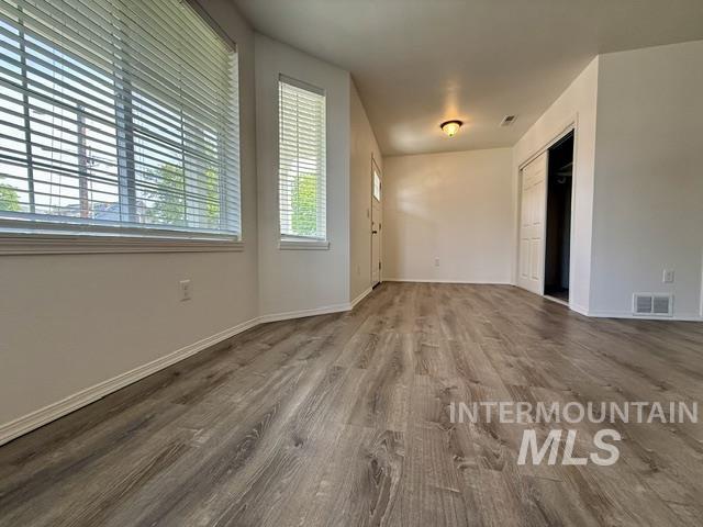 Spacious interior featuring wood-finish flooring, white baseboards, and multiple windows with blinds
