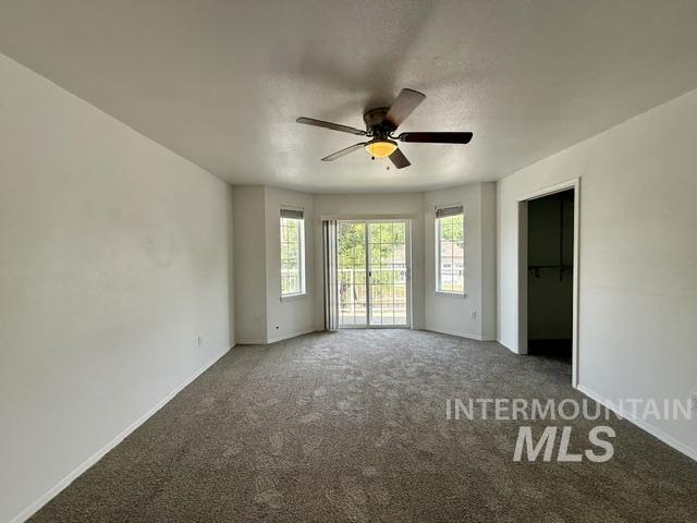 Carpeted room with a ceiling fan, bay windows, and sliding glass door
