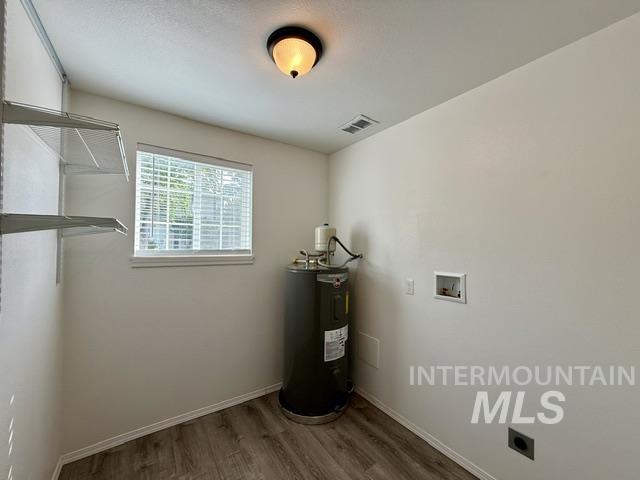 Utility room featuring wood-finish flooring, a contemporary semi-flush mount light fixture, wire shelving, and a window with blinds