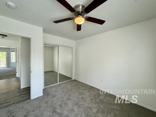 Bedroom featuring a ceiling fan with light fixture, mirrored closet doors, and grey carpeting
