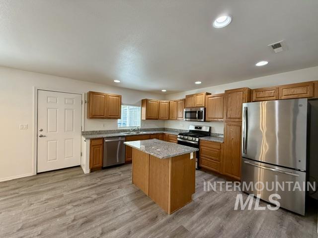 Contemporary kitchen featuring wood-finish cabinetry, granite-style countertops, and a central island