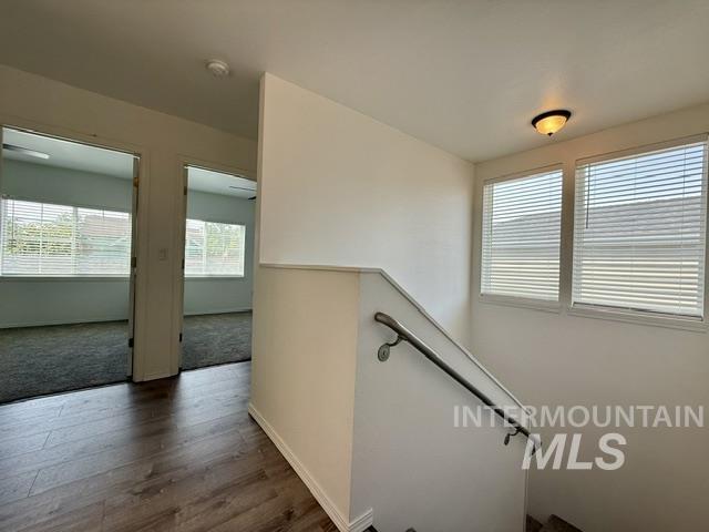 Upper landing with wood-finish flooring and a staircase featuring a metal handrail