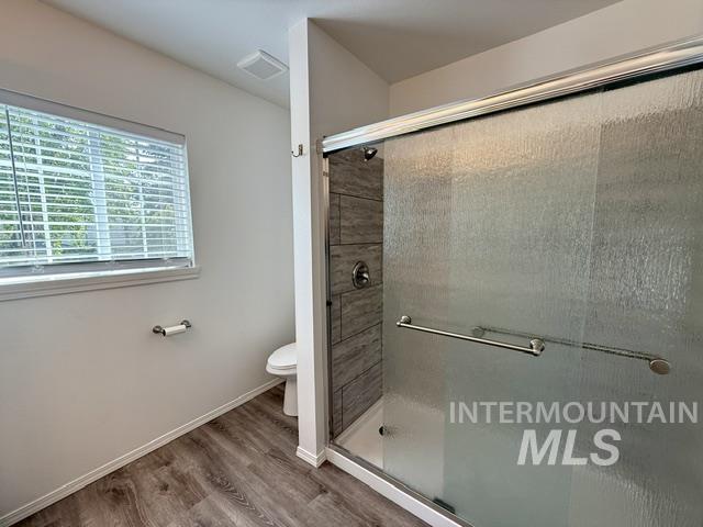 Shower enclosure featuring a sliding textured glass door and dark gray tile surround