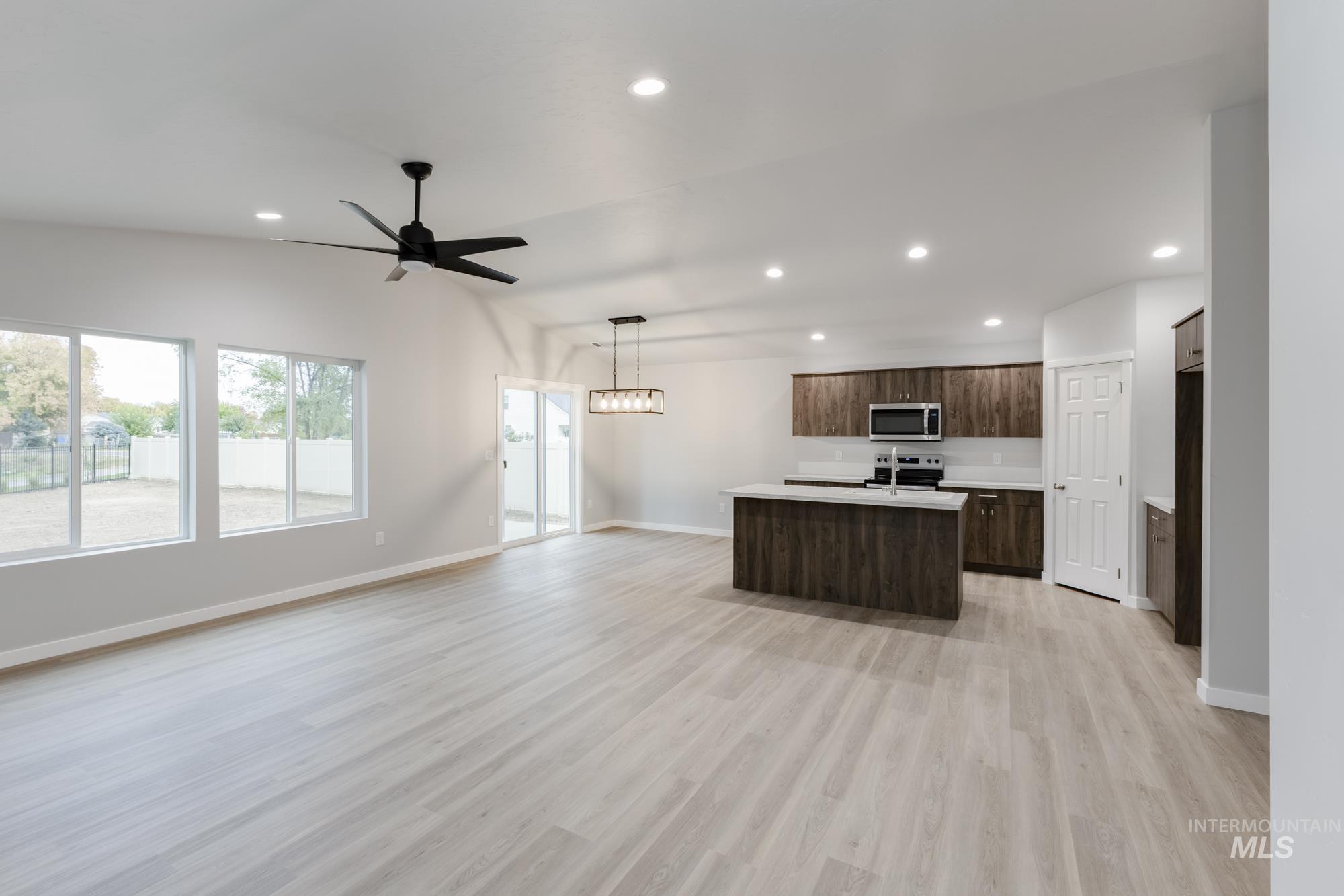 Kitchen featuring open floor plan, light countertops, recessed lighting, light wood-style flooring, and an island with sink