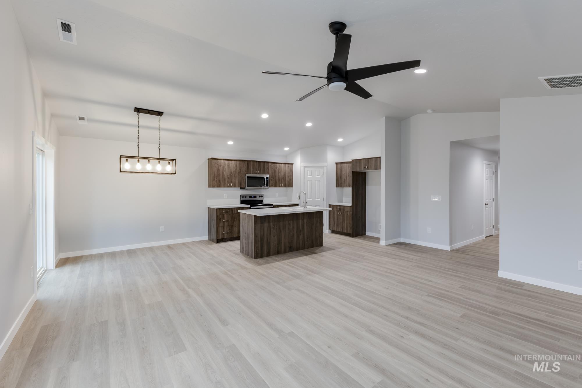 Kitchen with open floor plan, light countertops, a kitchen island with sink, light wood finished floors, and recessed lighting