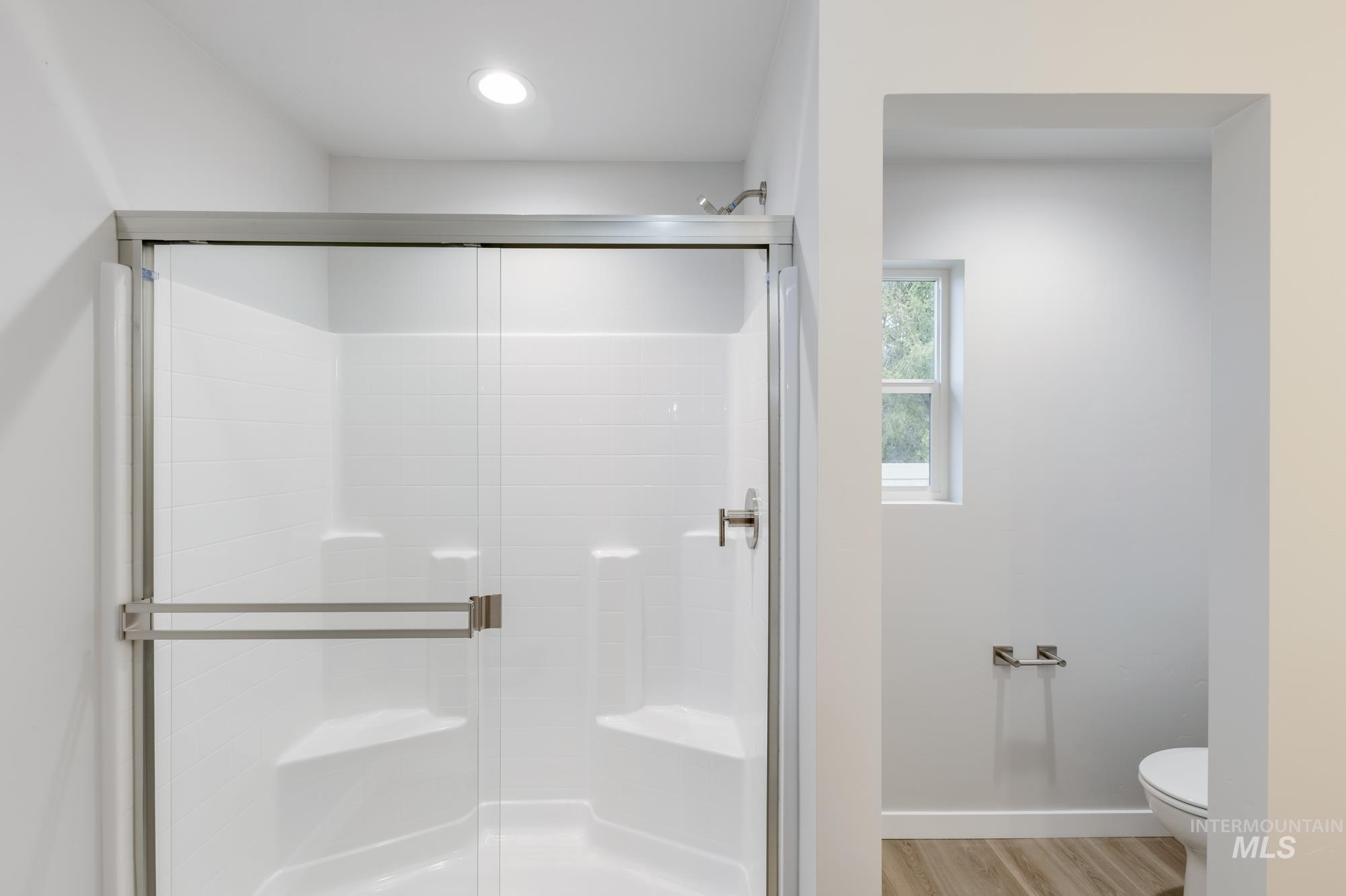 Full bath with a stall shower and light wood-type flooring