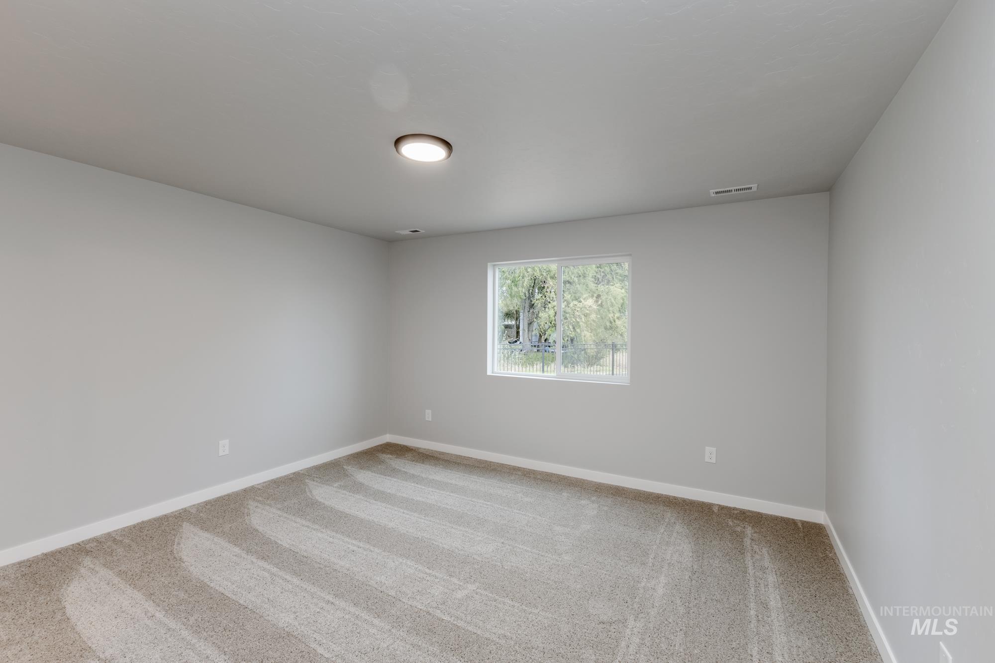 Empty room featuring light carpet and baseboards