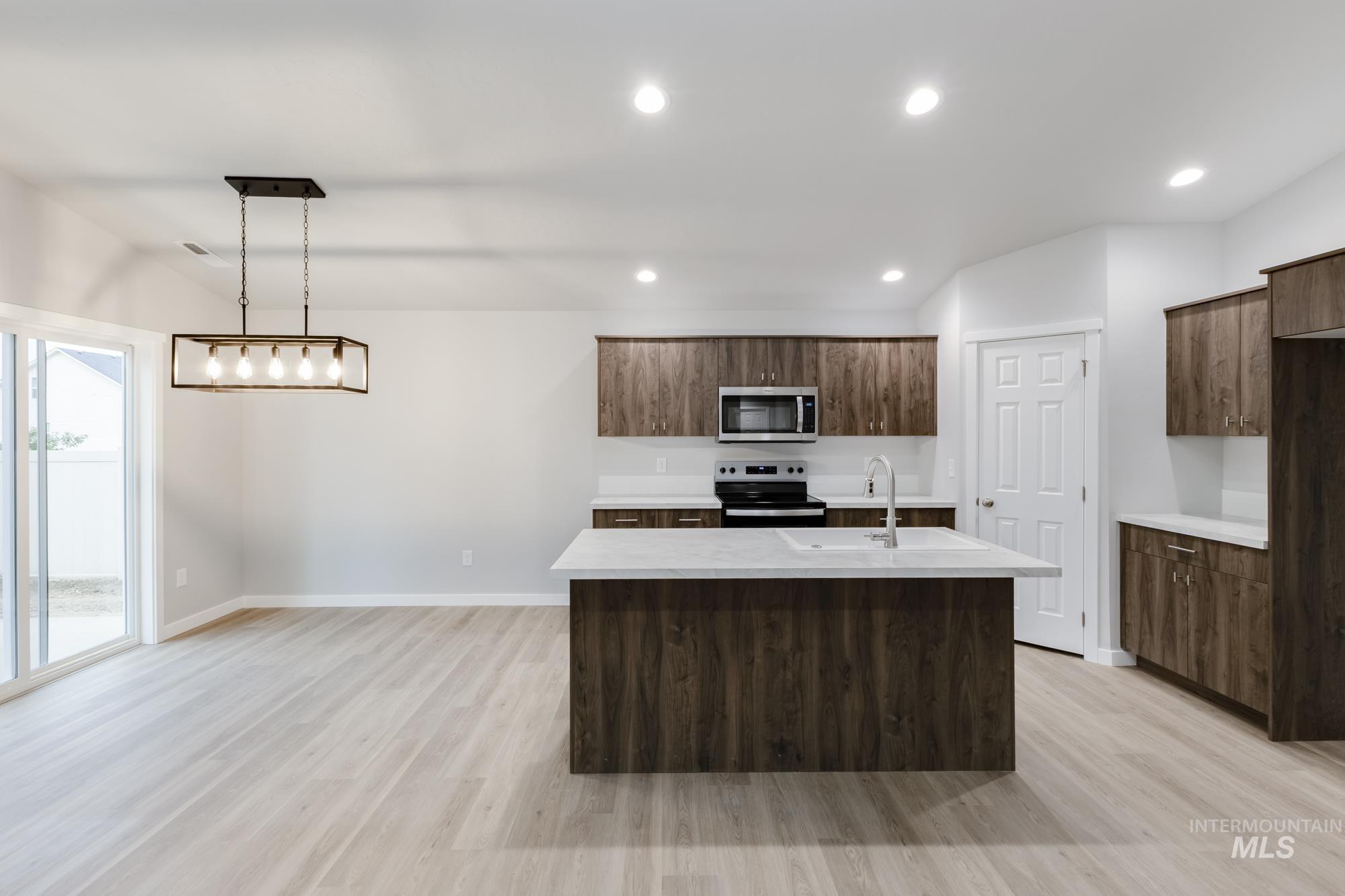 Kitchen with a center island with sink, decorative light fixtures, light wood-style flooring, stainless steel appliances, and recessed lighting