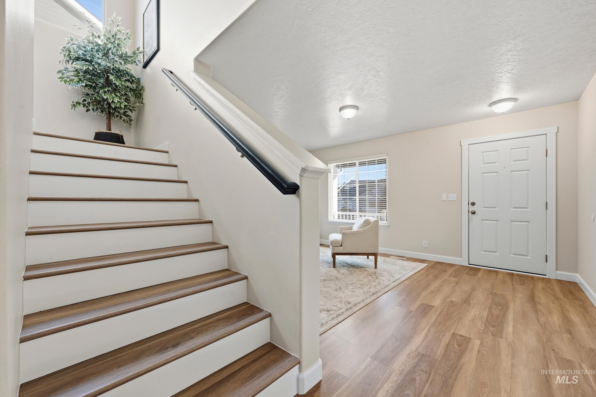 Entryway featuring a textured ceiling, light wood finished floors, and stairs