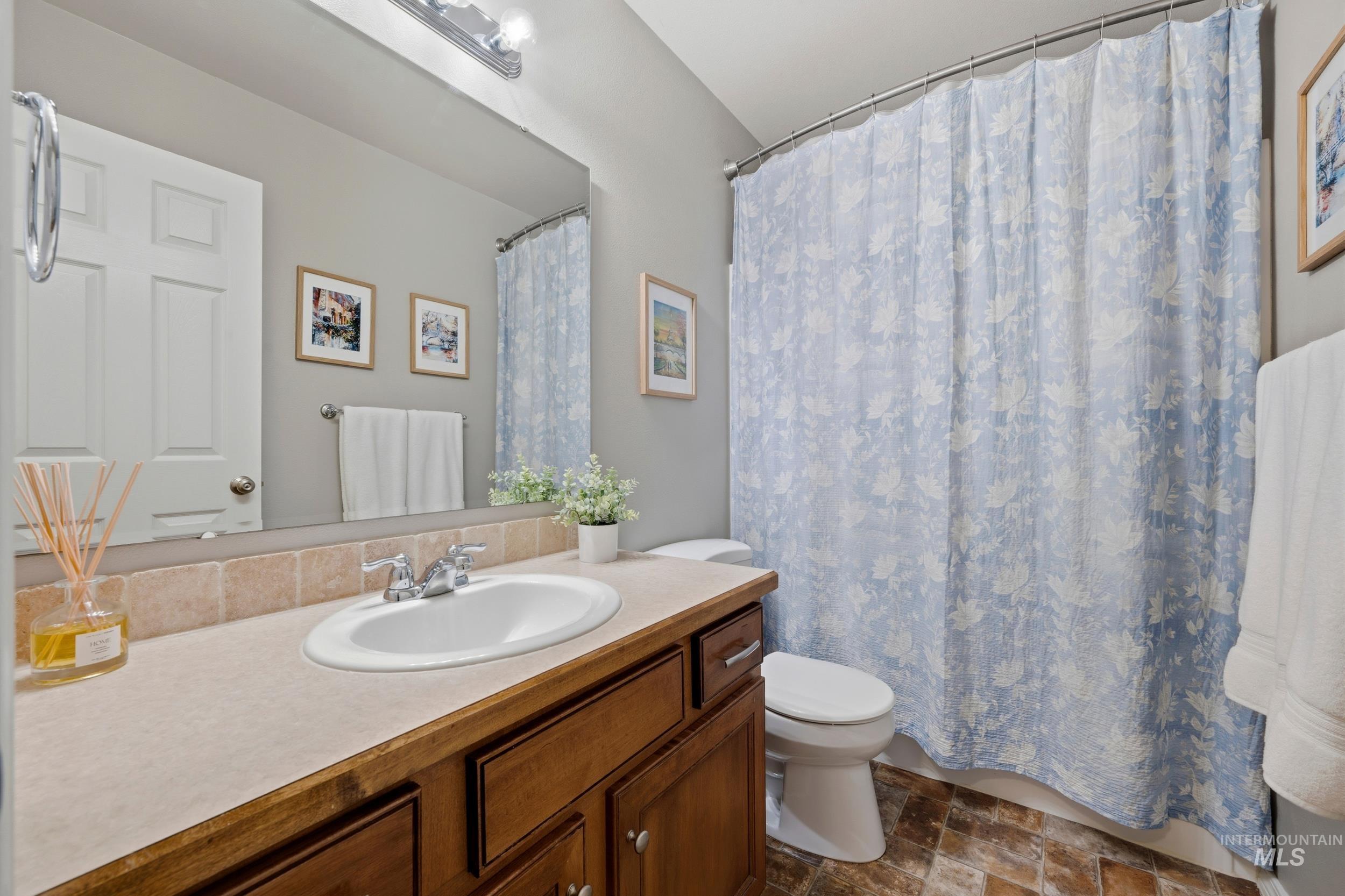 Bathroom with a shower with curtain, vanity, and stone finish flooring