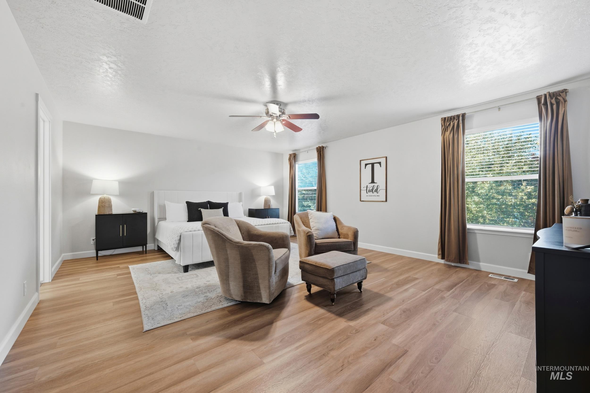 Bedroom featuring a textured ceiling, light wood-style flooring, and a ceiling fan