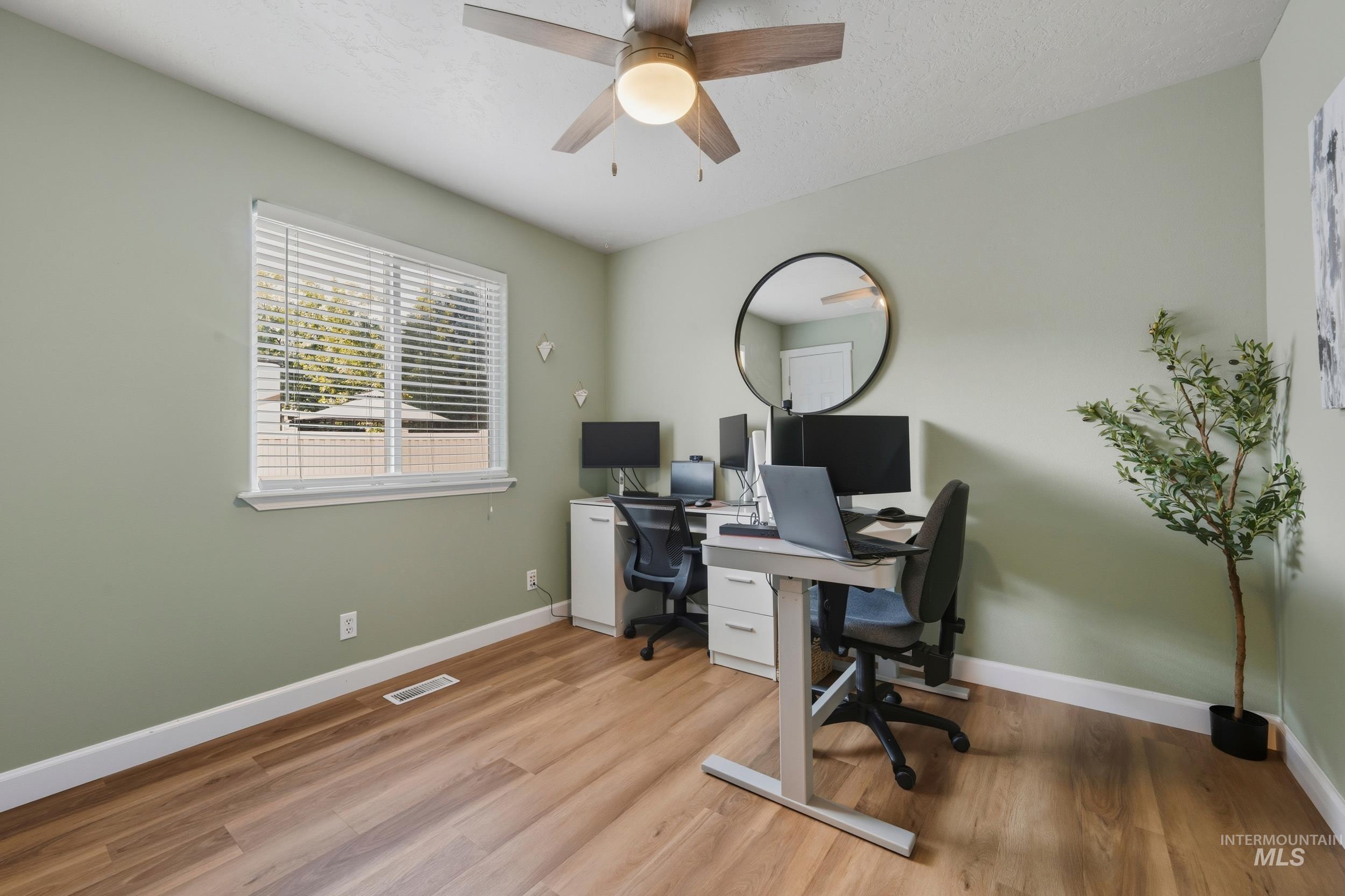 Office featuring light wood-style floors, a ceiling fan, and a textured ceiling