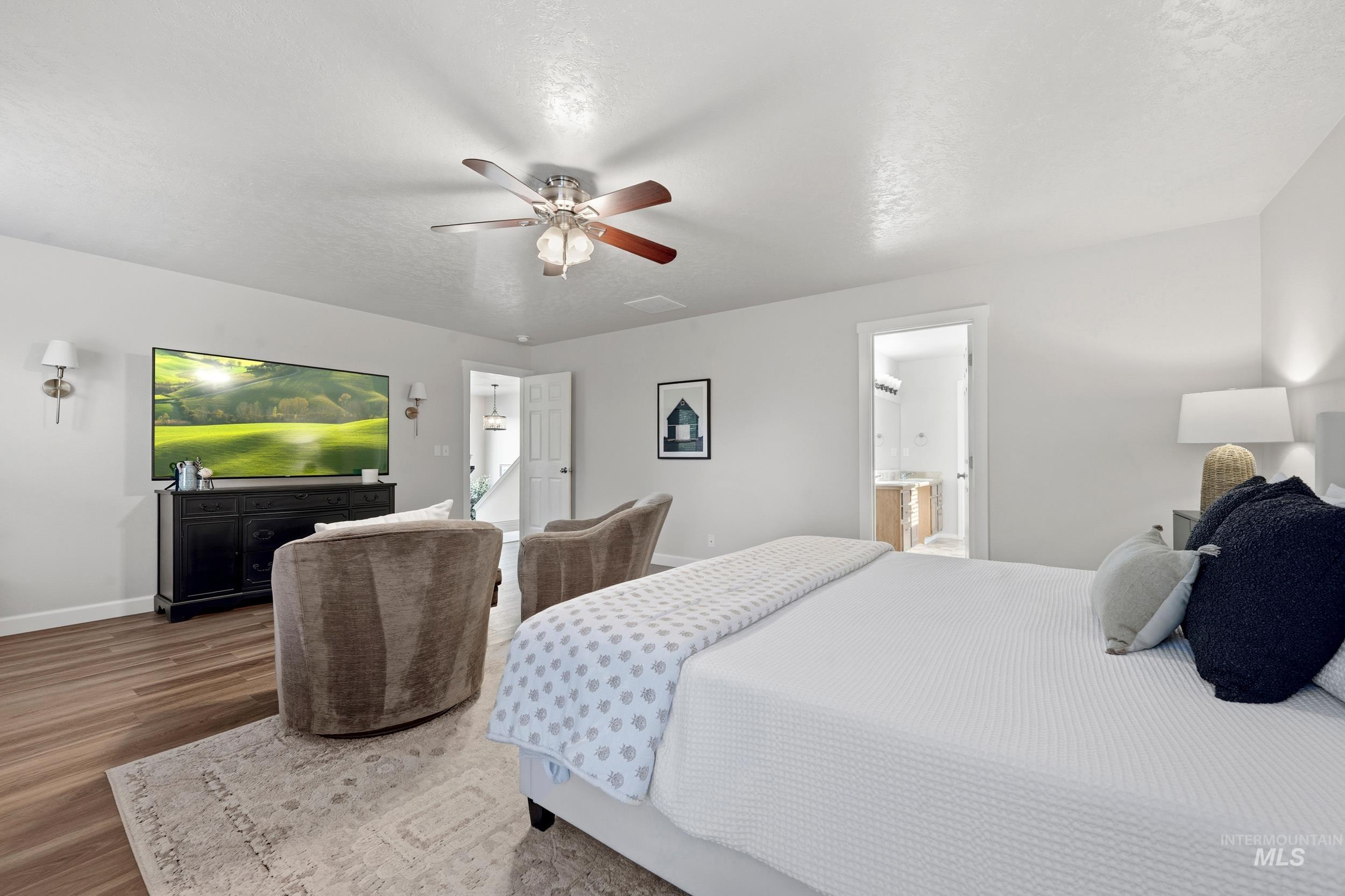 Bedroom featuring a textured ceiling, wood finished floors, ceiling fan, and ensuite bath