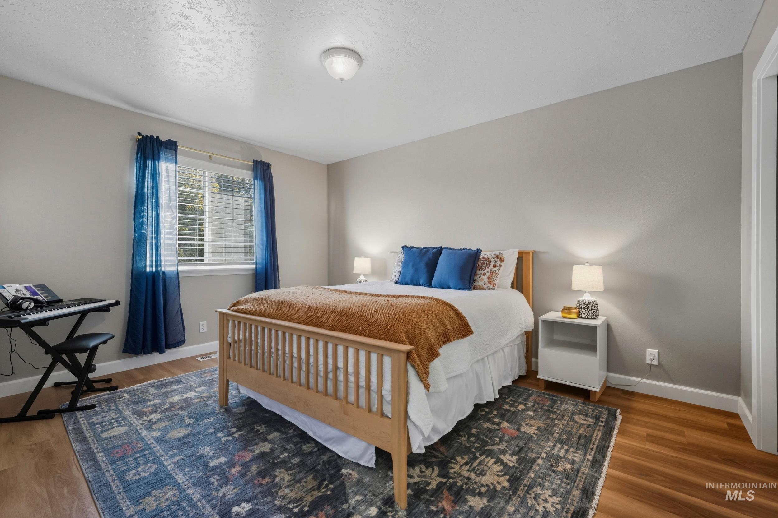 Bedroom with wood finished floors and a textured ceiling