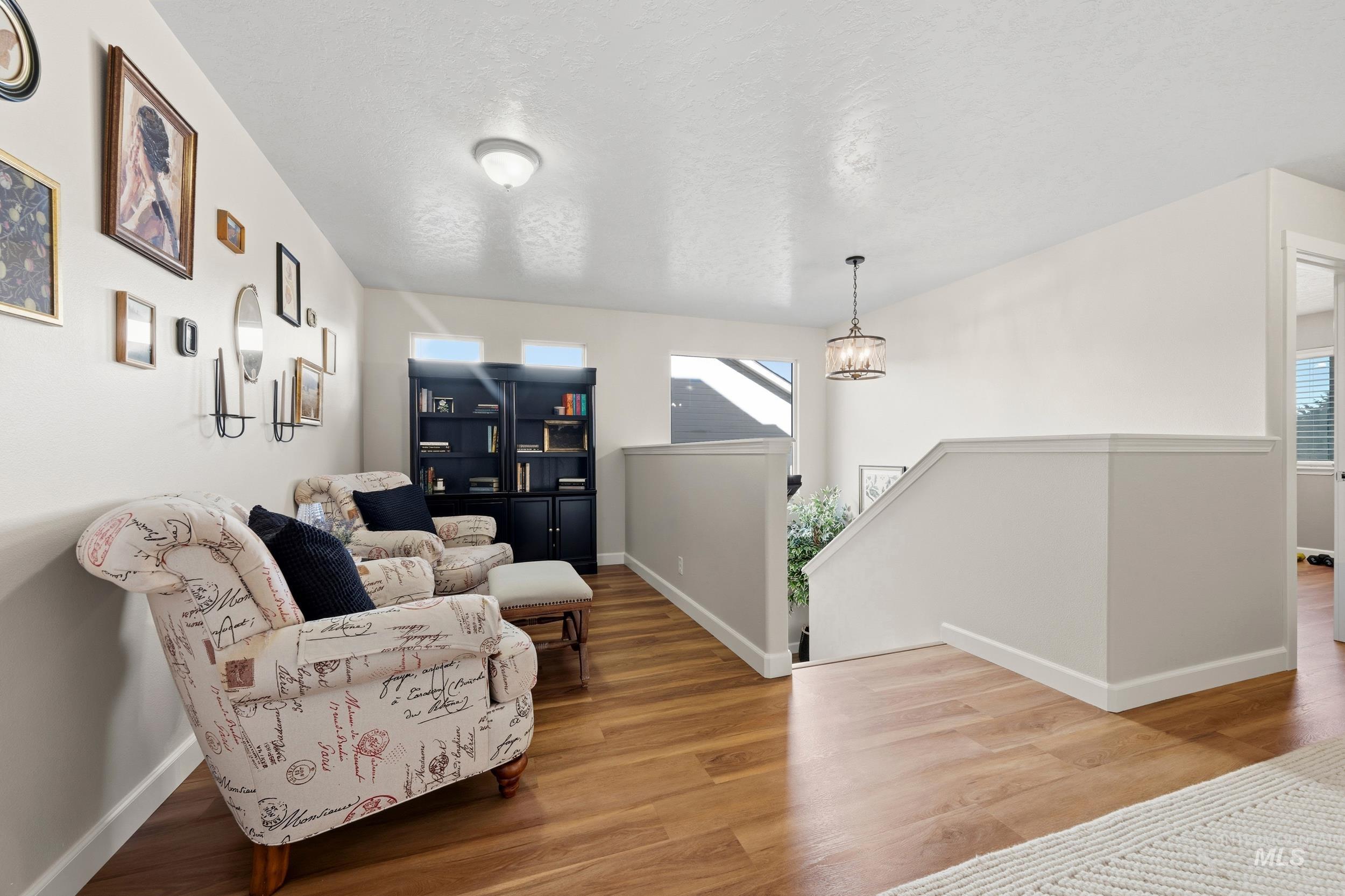Living area featuring an upstairs landing, wood finished floors, and a textured ceiling