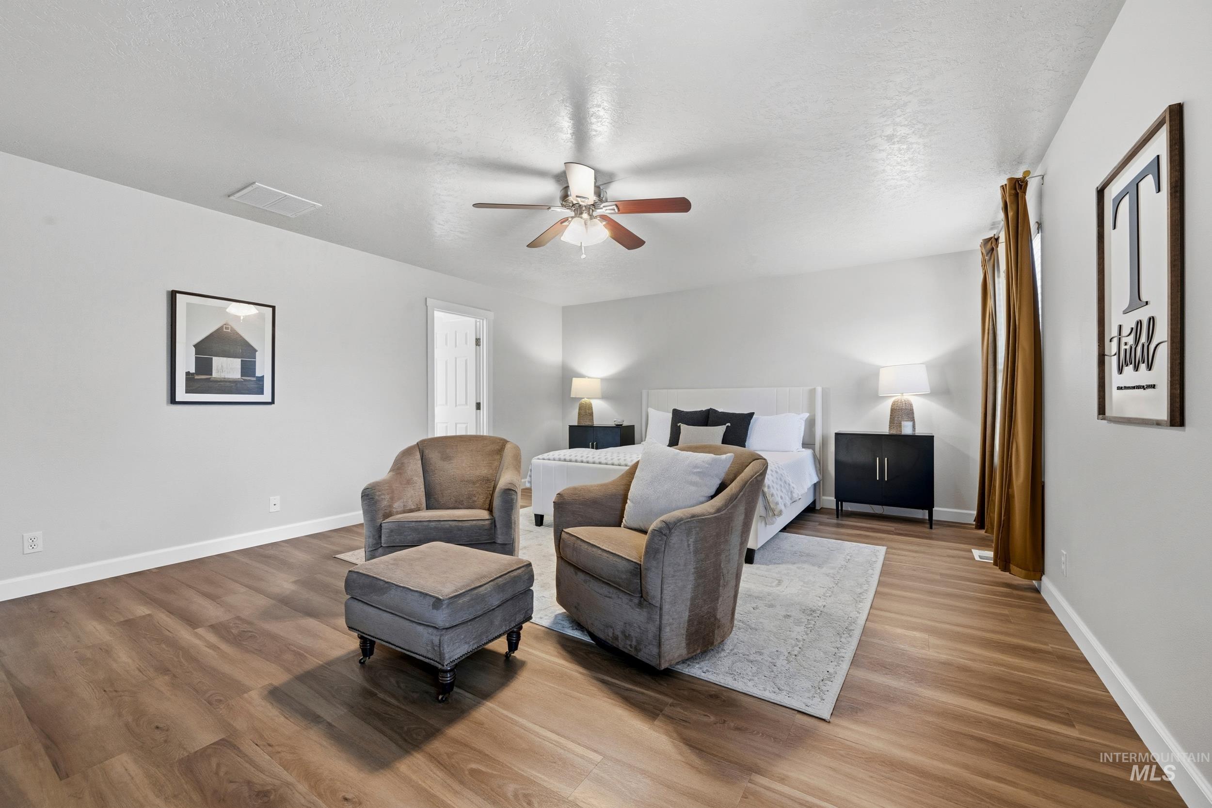 Bedroom with a textured ceiling, wood finished floors, and ceiling fan