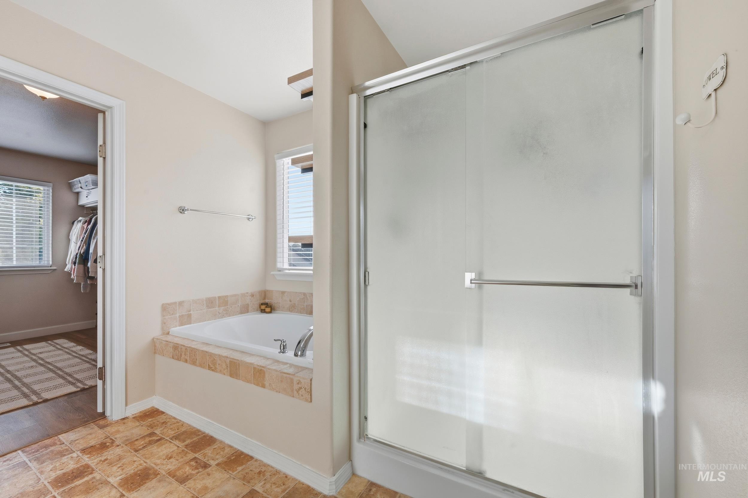 Full bathroom featuring a stall shower, a garden tub, and a walk in closet