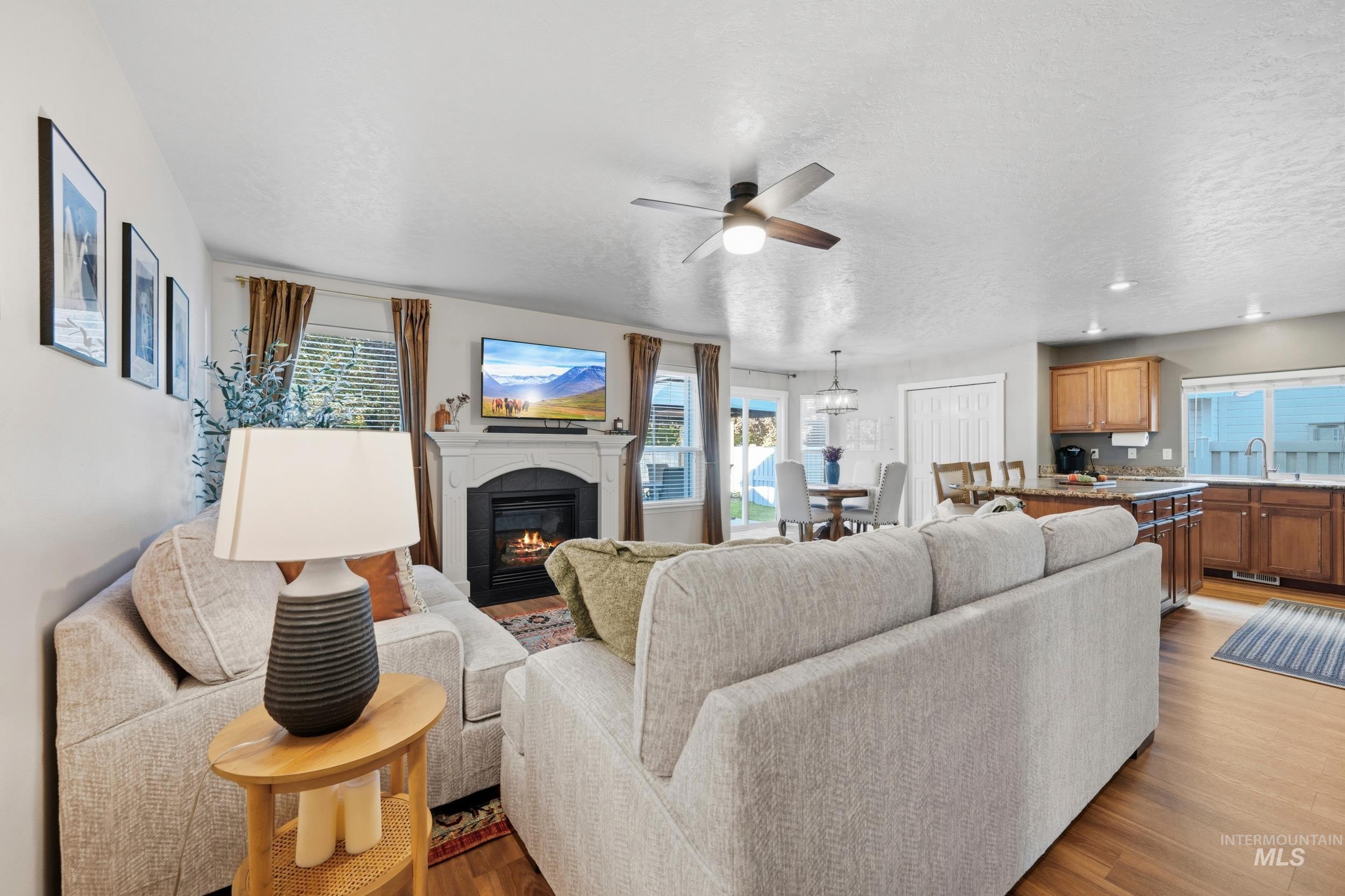 Living room featuring plenty of natural light, a glass covered fireplace, a ceiling fan, and a textured ceiling